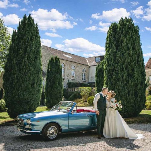 Mariés devant une salle de mariage 77 avec jardin et voiture ancienne